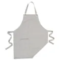 Grembiule in tela grigio chiaro con tracolla regolabile, tasca frontale e lacci laterali. - Grigio chiaro