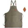 Detailed view of heavy-duty canvas apron with cross straps, leather patches and multiple pockets. - Brown Leather & Army Green