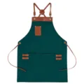 Dark green canvas apron with brown leather cross-back straps and multiple utility pockets. - Dark Green with Brown Leather
