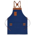 Blue canvas apron with brown leather cross straps and pockets, durable workwear for kitchen and cafe use. - Dark Blue with Brown Leather