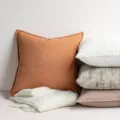 Detail view of textured chenille throw pillow and knit blanket in cozy home decor setup. - Caramel color