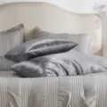 Détail de coussin de corps en satin montrant une texture soyeuse et une couleur grise. - Gris foncé
