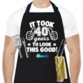 Vista detallada de un delantal de cocina negro para hombre con texto blanco divertido y bolsillos. - Estampado 40 Cumpleaños / Negro