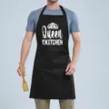Black kitchen apron with Queen of the Kitchen print, adjustable neck strap and useful front pocket. - Black Queen