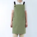 Green cotton apron with black straps and pockets, ideal for kitchen, cooking, and housework. - Olive Green