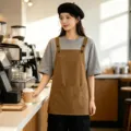 Delantal de trabajo marrón de lona, tirantes ajustables y bolsillo frontal para cocina y café. - Camel