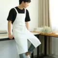 White cotton linen cross-back apron with pockets, minimalist style for kitchen or cafe. - White