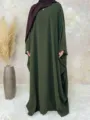 Detail view of the loose green batwing dress with hijab styling in a warm indoor cozy setting. - S / Dresses / Dark Green