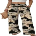 Detailed view of high-waisted wide-leg trousers featuring a stylish tropical palm leaf print. - Multi-color
