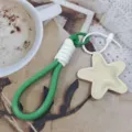 Close-up detail of green braided phone lanyard keychain featuring a cute beige star charm pendant. - Star Style 3