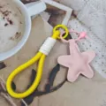 Yellow braided phone strap detail with pink star pendant on cozy tabletop coffee background. - Star Style 5