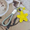 Close-up detail of the grey braided rope phone lanyard featuring a bright yellow star leather pendant. - Star Style 6