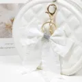 White quilted round bag with rhinestone bow keychain detailed charm accessory for women. - Style 5