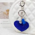 Gros plan détaillé d'un porte-clés cœur en strass bleu scintillant avec pompon et clochette. - Bleu