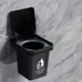 Wall-mounted black trash can with lid, sleek hanging waste basket for bathroom and kitchen use. - Black