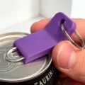 Purple plastic can opener keychain close up detail, portable bottle opener tool for soda drinks. - Purple