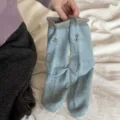 Primo piano dettagliato di calzini in maglia azzurra con risvolti grigi e delicato ricamo. - Taglia unica / Blu