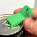 Detail view of the green plastic can opener pull tab tool with metal keyring for easy opening. - Green