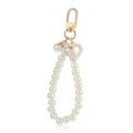 Detailed closeup of the elegant imitation pearl keychain strap with heart charm and gold clasp. - White