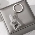 Detailed close-up shot of the transparent resin fish keychain resting elegantly on a soft grey box. - Black Small Fish