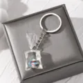 Detailed close-up of a resin transparent water bag fish keychain pendant with metal ring. - Colorful Fish