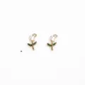Gedetailleerd overzicht van twee kleine geëmailleerde rozenbloemhangers met gouden randen. - Roze