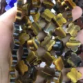 Close-up detail of Tiger's Eye four-leaf clover shaped stone beads for jewelry making - 14x14x5mm (Approx 28 Units) / Tiger's Eye