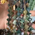 Close-up of 12mm faceted clover-shaped natural stone beads for jewelry making - Indian Agate