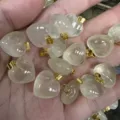 Nahaufnahme von 16 mm herzförmigen Anhängern aus klarem Stein mit goldenen Ösen für DIY - 16x9mm / Zitronenquarz