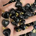 Nahaufnahme von 16 mm herzförmigen schwarzen Natursteinanhängern mit Goldösen. - 16x9mm / Obsidian