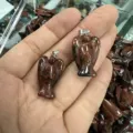 Detaillierte Makroansicht von zwei aus Naturstein geschnitzten Engelanhängern in der Hand - 18*25mm / Mahagoni-Obsidian