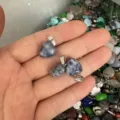 Detailansicht von 12 mm herzförmigen Anhängern aus blauem Naturstein in der Hand - 12x6mm / Blaupunktstein