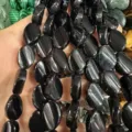 Vista dettagliata di perle ovali in pietra naturale nera lucida con fori verticali per gioielli - Agata nera