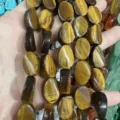 Primo piano di perle ovali in occhio di tigre naturale con chatoyancy dorato unico - Occhio di Tigre
