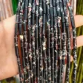 Detailed close-up of 4x13mm black imperial stone tubular beads for jewelry DIY. - 29 Pieces/Strand / Black Imperial Stone