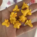 Macro view of bright yellow trumpet flower shaped acrylic beads for DIY jewelry crafts. - Yellow