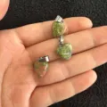 Nahaufnahme von drei 12-mm-herzförmigen Unakit-Natursteinanhängern in der Handfläche gehalten - 12x6mm / Unakit