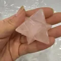 Hand die een doorschijnende roze rozenkwarts Merkaba ster edelsteen vasthoudt - 40mm / Rozenkwarts