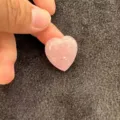 Gros plan d'une pierre d'agate rose en forme de cœur tenue entre les doigts pour la taille - Rose / 10mm