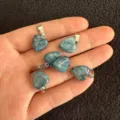 Mehrere 12 mm große blau gemaserte herzförmige Steinanhänger in der Hand zum Größenvergleich - 12x6mm / Blauer Achat