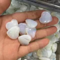 Pierres de cristal d'opalite polies en forme de cœur tenues dans une main humaine - Pierre en Vrac 20mm*6mm / Opale