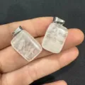 Detalle de dos colgantes rectangulares de cristal blanco natural sostenidos en la mano - 10 Piezas / Cristal de roca