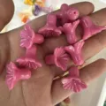 Macro detail of pink shell powder trumpet flower loose beads held in hand for DIY jewelry - Rose Red