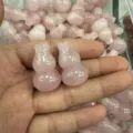 Eine Hand hält zwei natürliche rosa Rosenquarz-Kürbis-Anhänger für DIY-Schmuck - Ca. 18*30mm / Rosenquarz