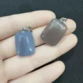 Detalle de dos colgantes rectangulares de ágata natural gris sostenidos en la mano para escala. - 10 Piezas / Ágata Gris