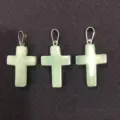 Close-up of three natural green aventurine cross pendants on black fabric background - Green Aventurine