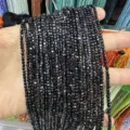 Close-up of strands of black faceted square cubic zirconia loose beads held in hand - Black Zirconia