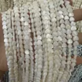 Nahaufnahme weißer herzförmiger Süßwassermuschelperlen mit Perlmuttglanz für DIY - Herzform mit vertikalem Loch / 约6mm(约63颗左右一条)