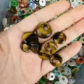 Close-up view of natural tiger eye stone donut beads held in hand for jewelry DIY - Tiger Eye