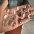 Primer plano de cabujones de cristal blanco sintético ovalados y redondos en mano - 3mm